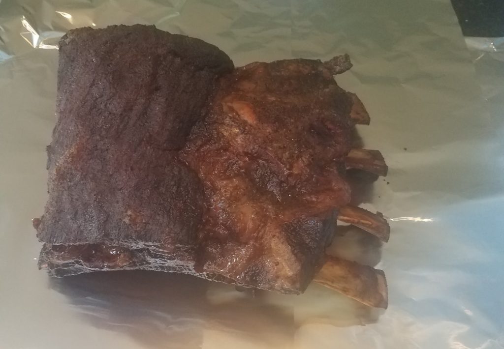 Cooked ribs with bones exposed on foil.