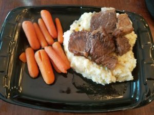 Short ribs on mashed potatoes with carrot on the side.
