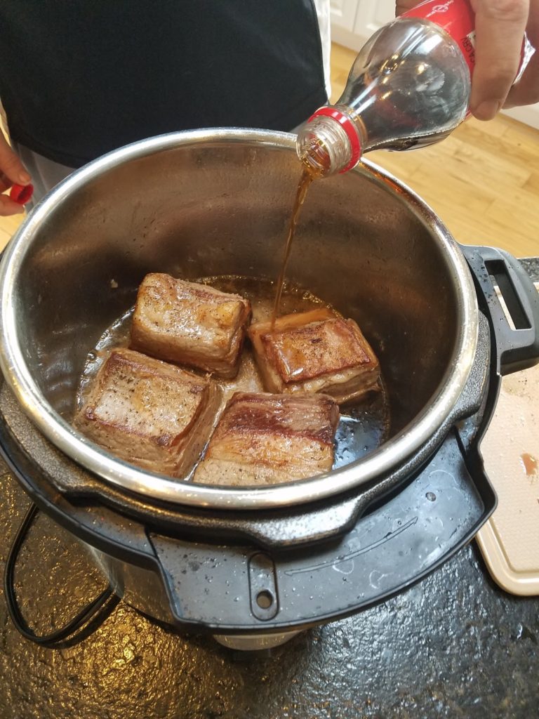 Pouring Cola over cooking ribs.