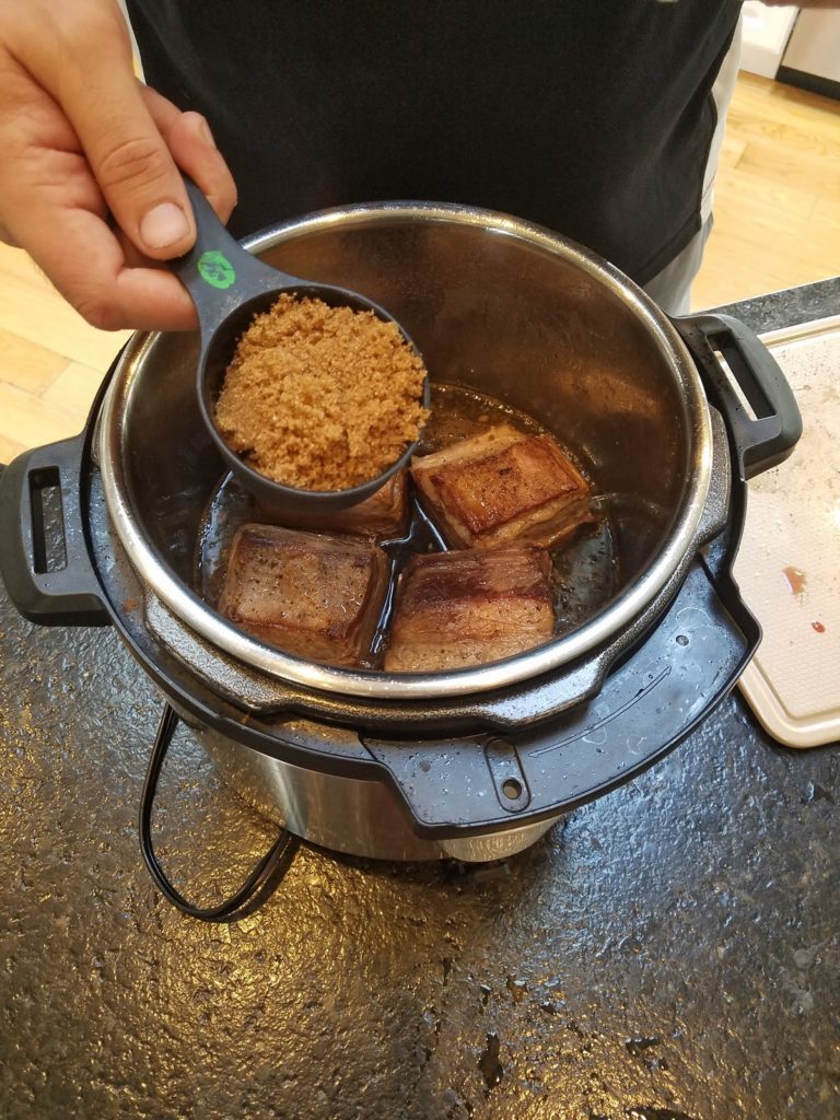 Pouring brown sugar over cooking ribs.