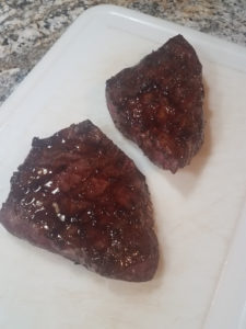 Cooked steaks covered in glaze.